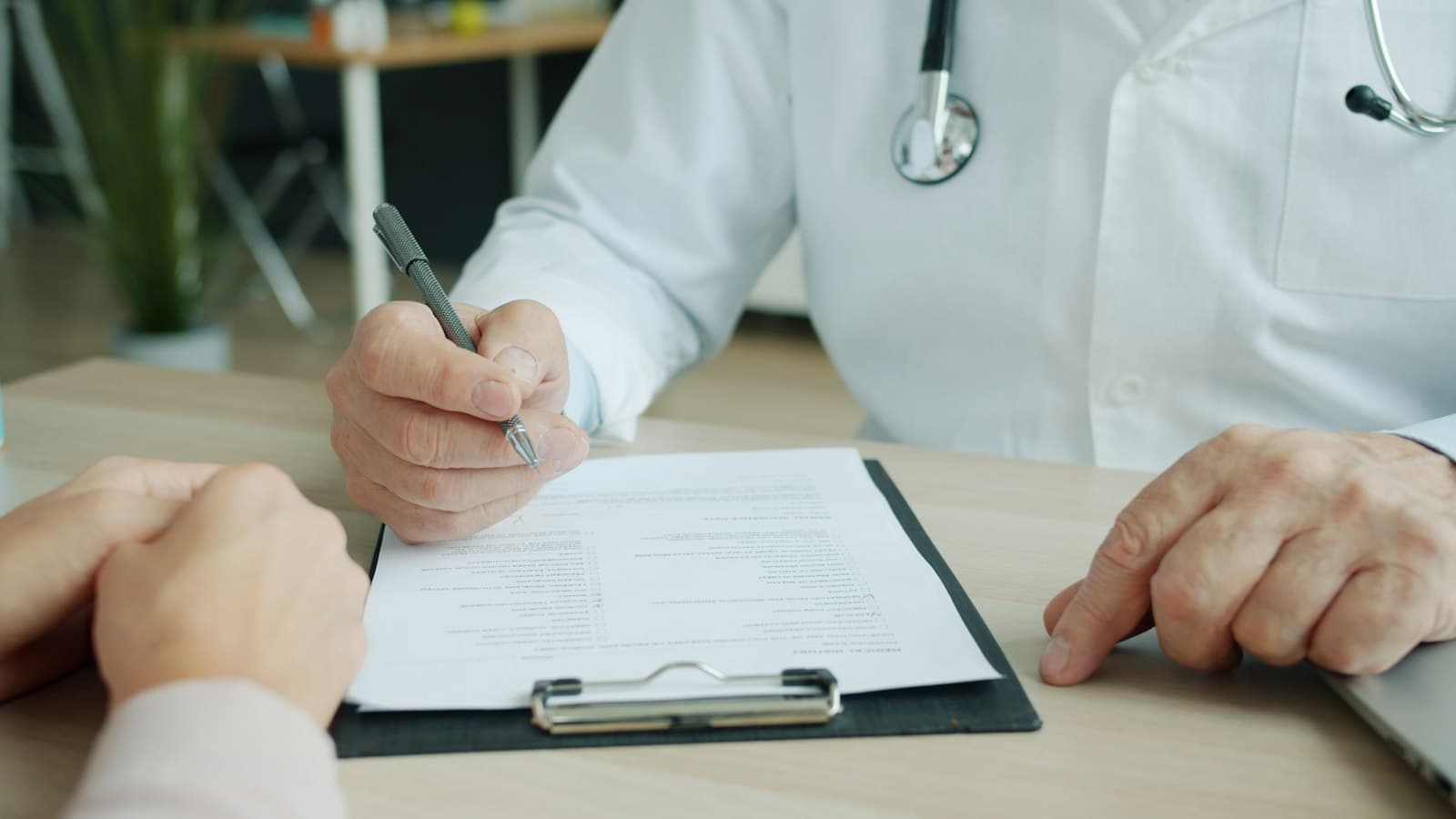 Médecin rédigeant sur le dossier d'un patient